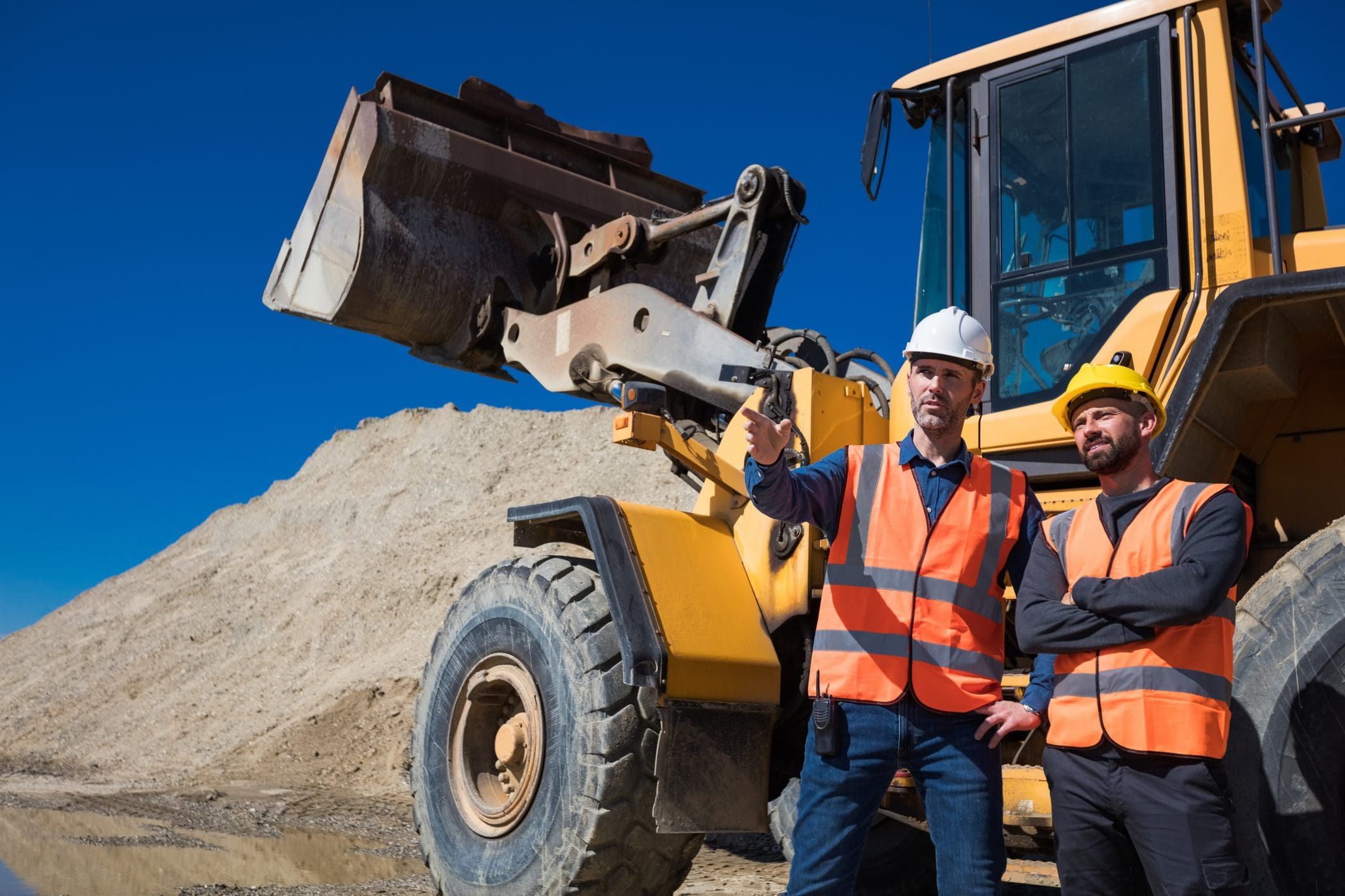 Construction workers discussing near heavy machinery.