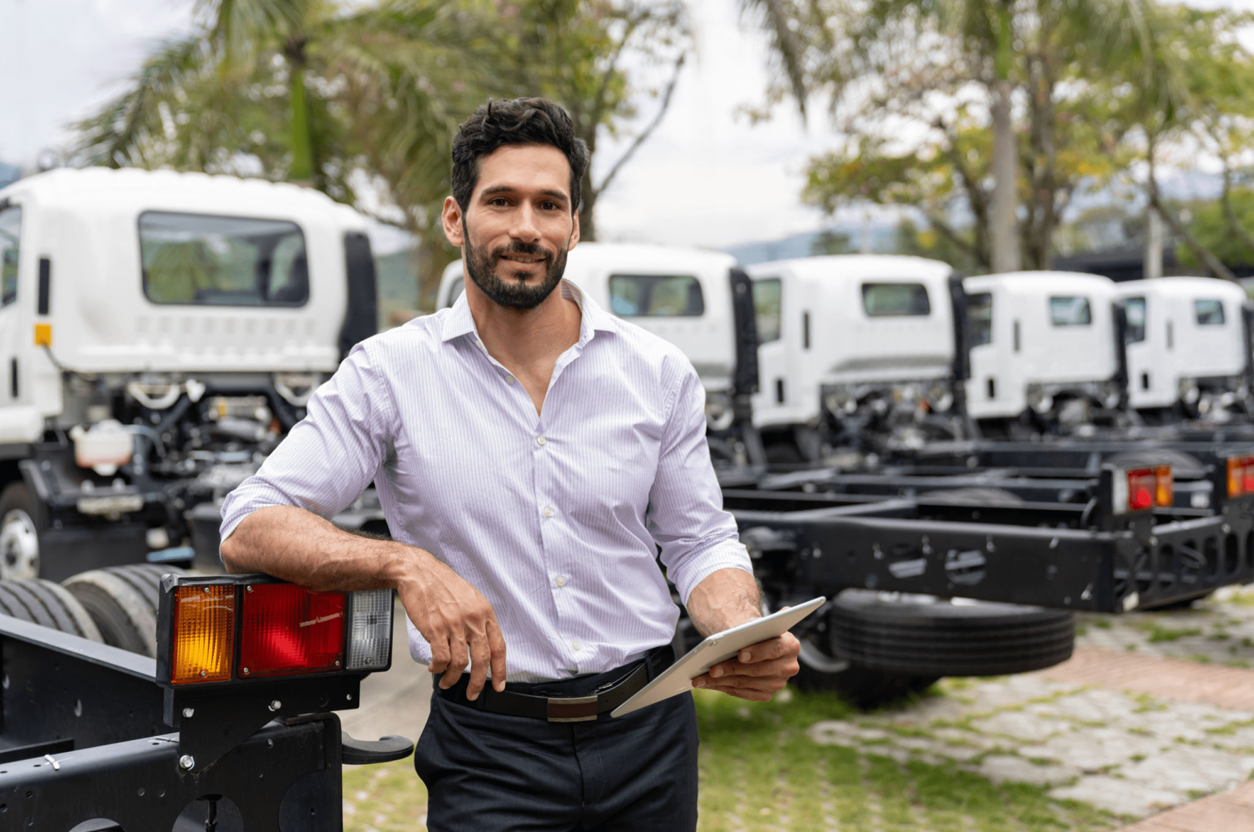 Man holding tablet near truck chassis outdoors.